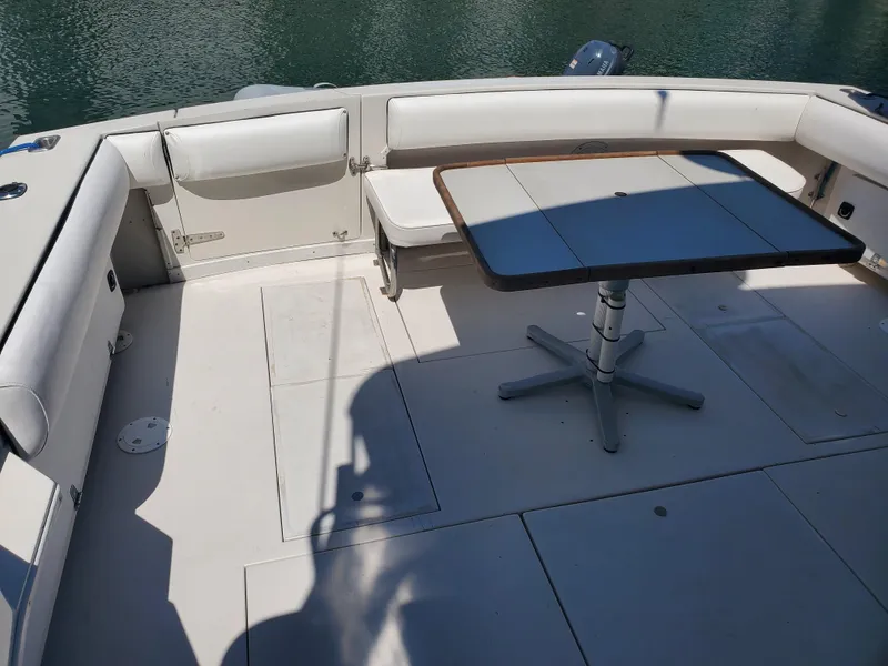 Slide: The Image of 1991 Wellcraft 3300 Sport Bridge boat deck with seating and table, near water. - 22