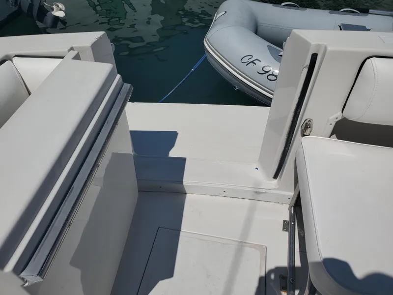 Slide: The Image of 1991 Wellcraft 3300 Sport Bridge interior with seating, docked near inflatable boat. - 24