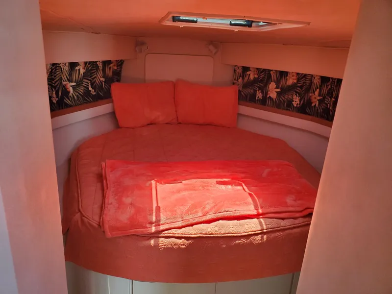 Slide: The Image of Cozy cabin interior of 1991 Wellcraft 3300 Sport Bridge with orange bedding and floral accents. - 3