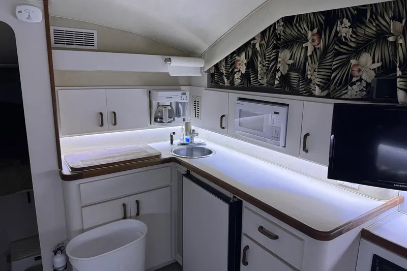 Slide: The Image of 1991 Wellcraft boat kitchen with microwave, sink, and floral wallpaper. - 8