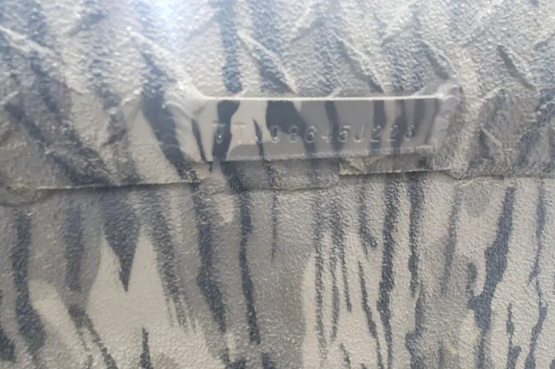 Slide: The Image of Close-up of textured surface with a metal plate, featuring a serial number. - 12