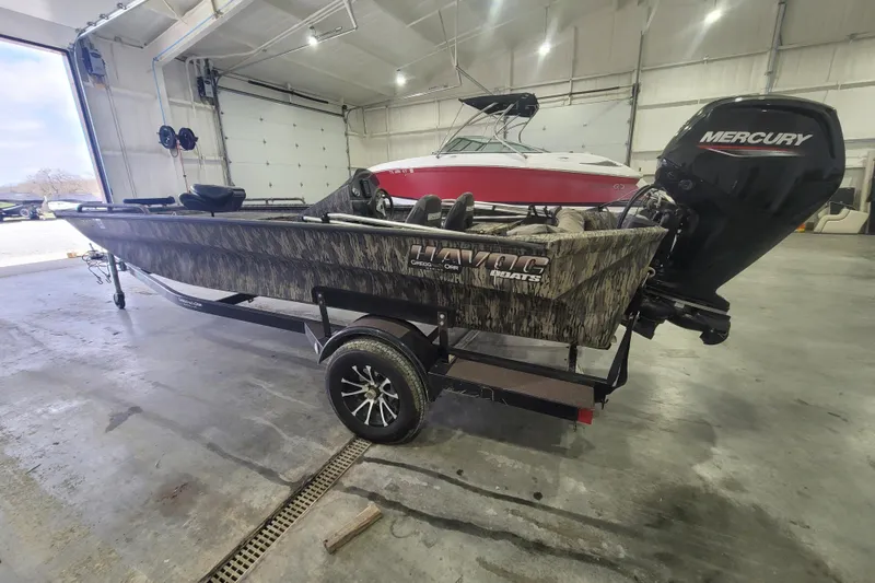 Slide: The Image of 2023 Havac FRRSC boat with camouflage design and Mercury engine in a garage. - 6