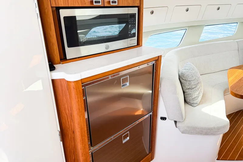 Slide: The Image of 2018 Intrepid 438 Evolution yacht interior with microwave, fridge, and seating area. - 51