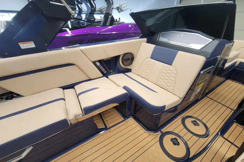 Slide: The Image of 2025 MasterCraft X24 boat interior with beige and navy seating, teak flooring. - 12