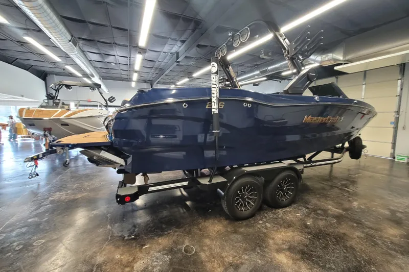 Slide: The Image of 2025 MasterCraft X24 boat in showroom, sleek design, on trailer, indoor lighting. - 3