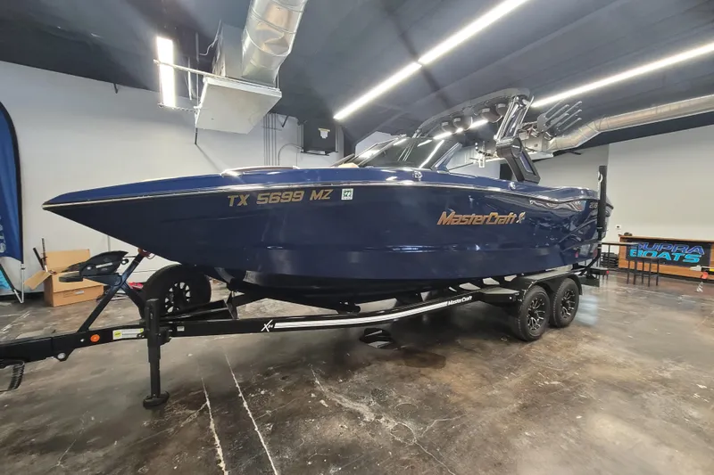 Slide: The Image of 2025 MasterCraft X24 boat in showroom, blue exterior, on trailer. - 7