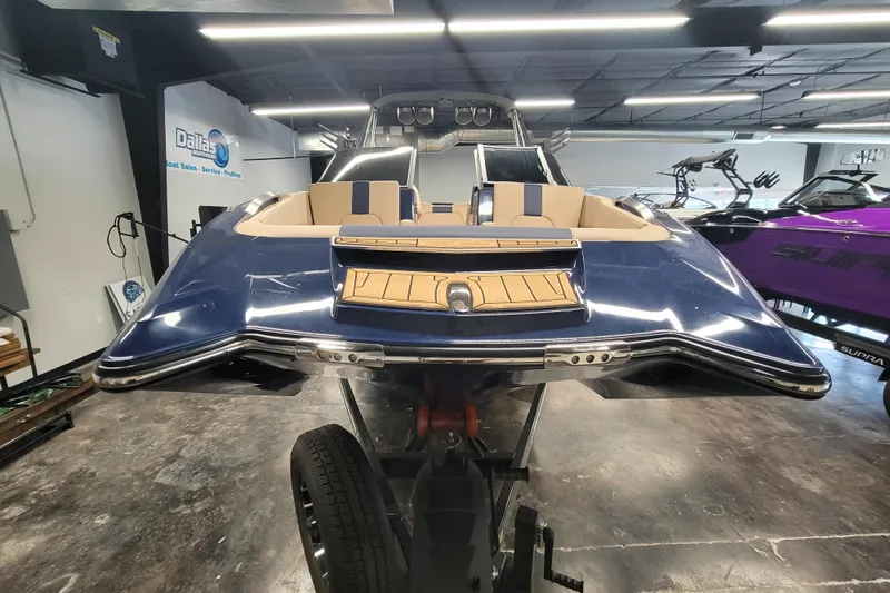 Slide: The Image of 2025 MasterCraft X24 boat in showroom, blue exterior, beige interior, on trailer. - 8