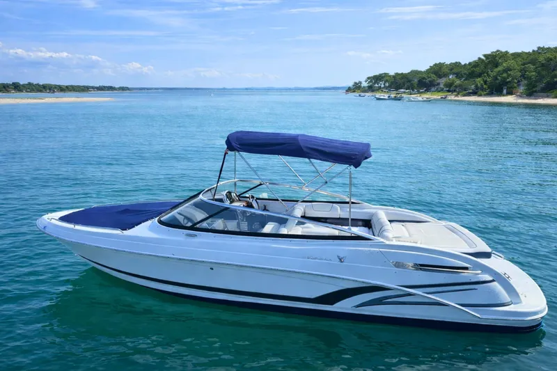 Slide: The Image of 2015 Formula 240 Bowrider boat on clear blue water near a scenic shoreline. - 1