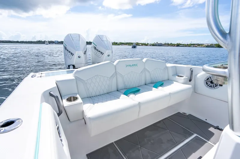 Slide: The Image of Luxury Dynamic D-305V 2024 boat interior with plush seating and twin engines on a serene lake. - 22