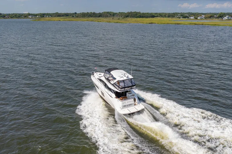 Slide: The Image of 2017 Sea Ray Fly 510 yacht cruising on open water, surrounded by scenic landscape. - 5