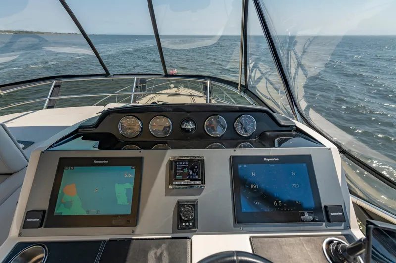 Slide: The Image of 2017 Sea Ray Fly 510 yacht dashboard with navigation screens and ocean view. - 73