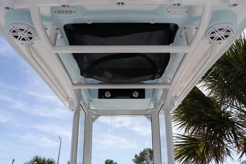 Slide: The Image of 2026 Caymas 24 HB boat T-top with speakers and storage, under clear blue sky. - 14