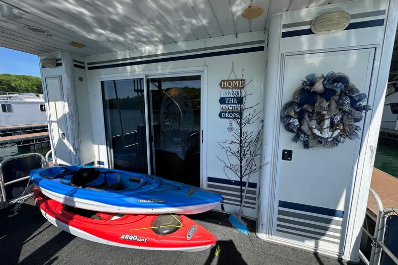 Slide: The Image of Houseboat deck with kayaks, nautical decor, and "Home is where the anchor drops" sign. Starlite 15x67, 2001. - 12