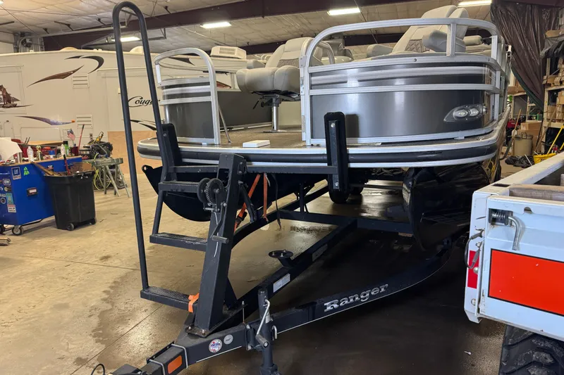 The Image of 2023 Ranger Reata 220F pontoon boat on trailer in a workshop. - 1