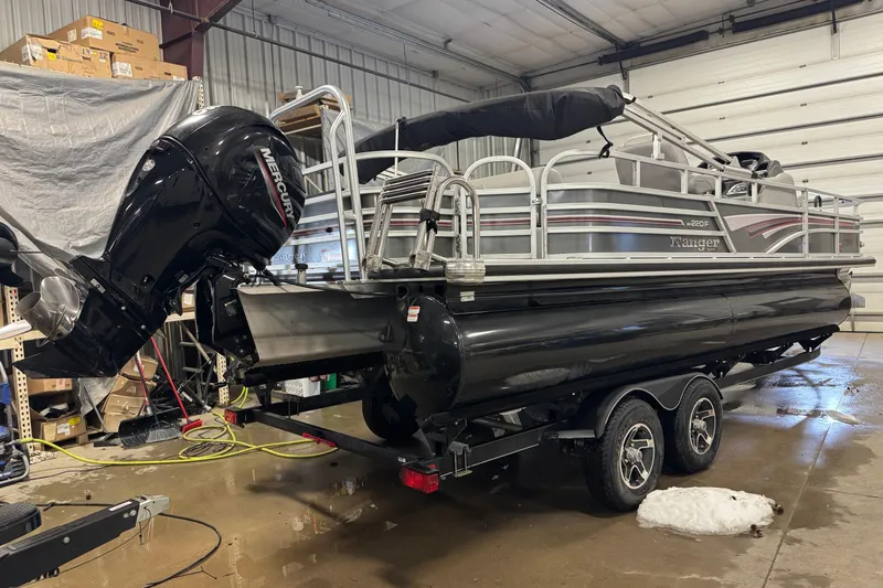 Slide: The Image of 2023 Ranger Reata 220F pontoon boat in a garage with Mercury outboard motor. - 3