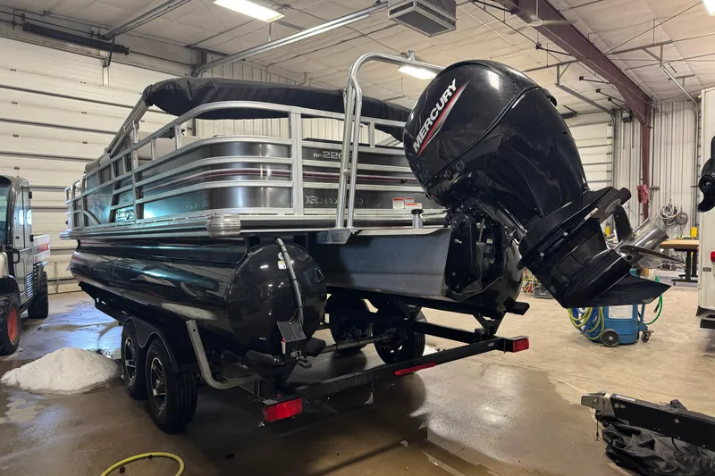 Slide: The Image of 2023 Ranger Reata 220F pontoon boat with Mercury outboard motor in a garage. - 4