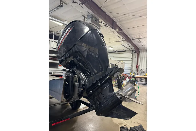 Slide: The Image of 2023 Ranger Reata 220F with Mercury outboard motor in a garage setting. - 5