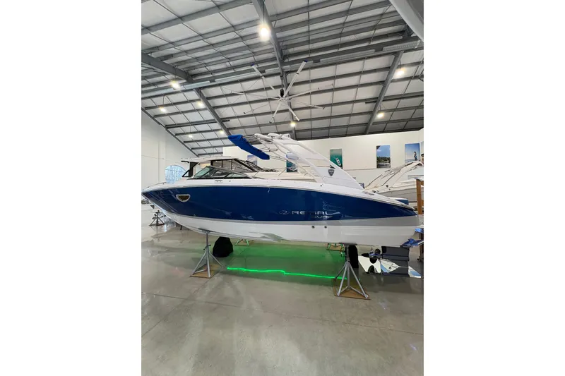 The Image of 2026 Regal LS6 Surf boat in showroom, blue and white design, elevated on stands. - 1