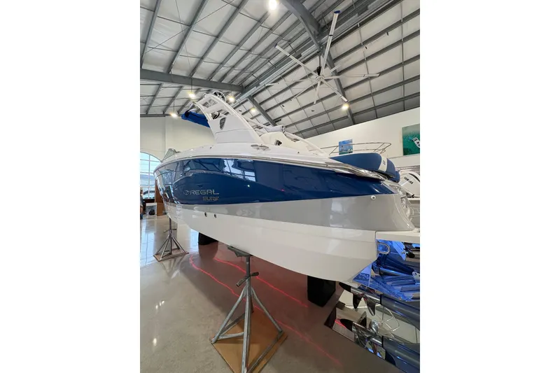 Slide: The Image of 2026 Regal LS6 Surf boat displayed in a showroom, featuring sleek blue and white design. - 38