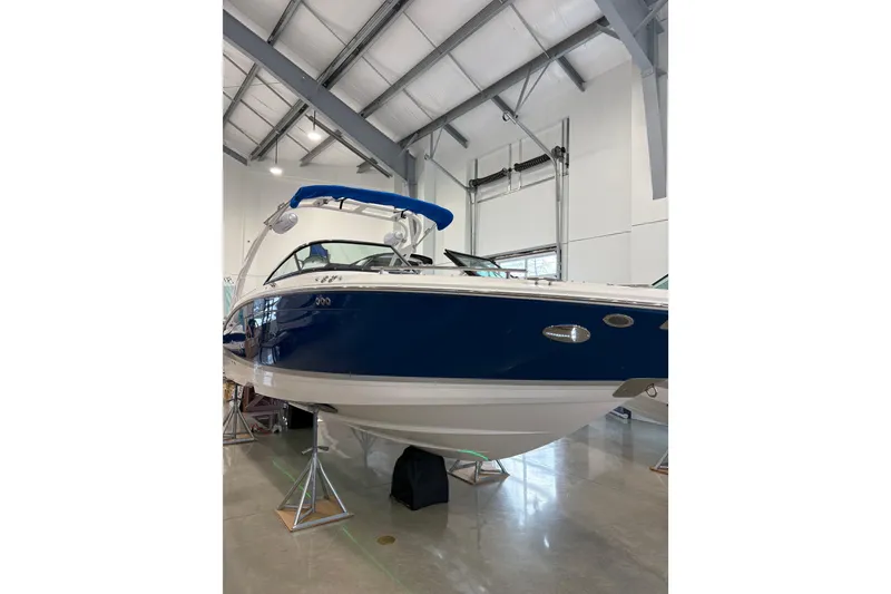 Slide: The Image of 2026 Regal LS6 Surf boat in showroom, blue and white design, elevated on stands. - 5