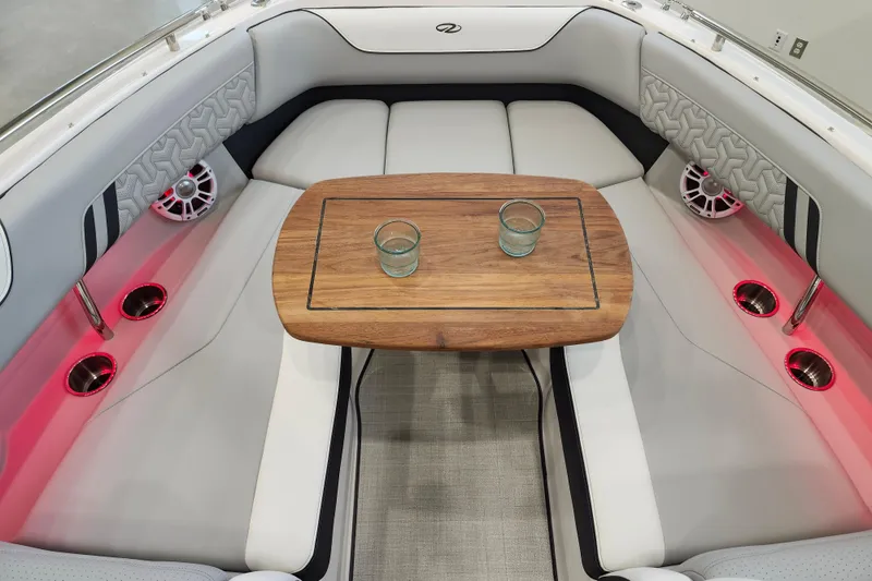 Slide: The Image of 2025 Regal LX6 boat interior with wooden table, cushioned seating, and ambient red lighting. - 33
