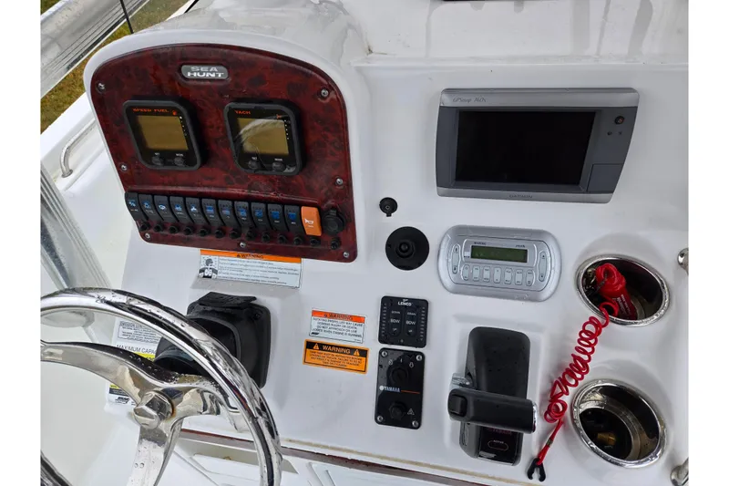 Slide: The Image of 2012 Sea Hunt Ultra 234 dashboard with steering wheel, gauges, and navigation equipment. - 12