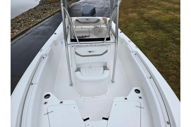 Slide: The Image of 2012 Sea Hunt Ultra 234 boat interior with seating and console, docked near grassy shore. - 20