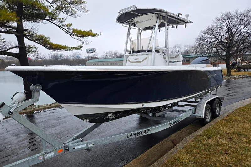 Slide: The Image of 2012 Sea Hunt Ultra 234 boat on trailer by a lakeside road. - 8