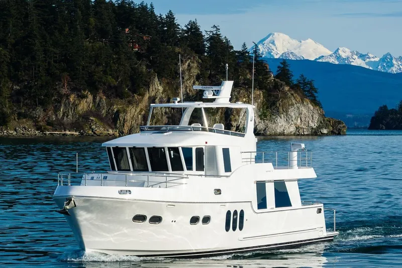 The Image of Luxury Northwest 55 yacht cruising near scenic forested coastline, 2024 model. - 0