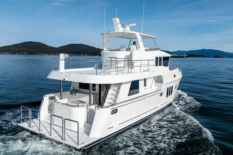 Slide: The Image of 2024 Northwest 55 yacht cruising on serene waters with scenic island backdrop. - 2
