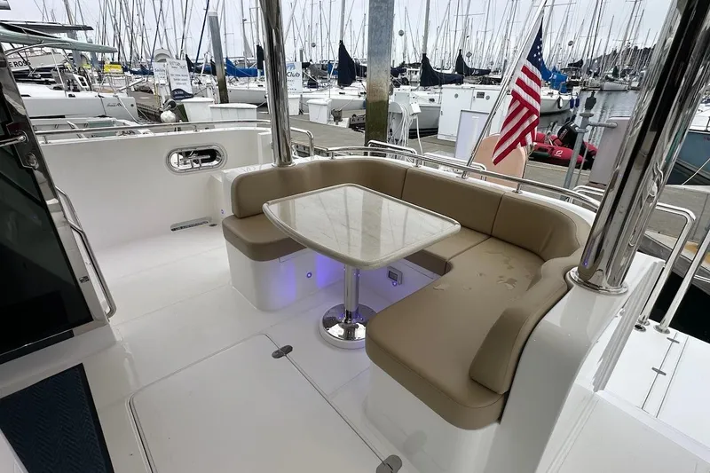 Slide: The Image of Luxurious seating area on 2024 Northwest 55 yacht, featuring a sleek table and American flag. - 20