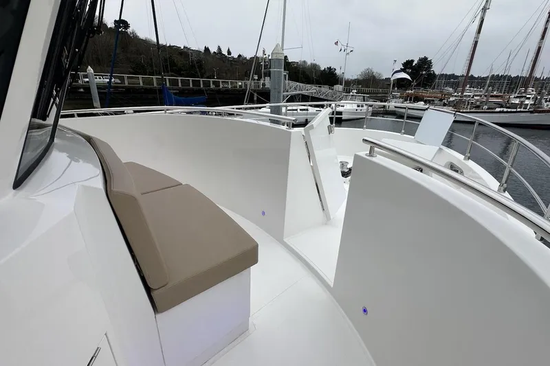 Slide: The Image of 2024 Northwest 55 yacht deck with cushioned seating and railing, docked at marina. - 27