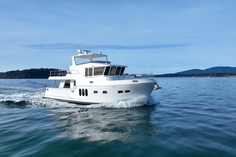 Slide: The Image of 2024 Northwest 55 yacht cruising on calm waters with scenic mountain backdrop. - 4