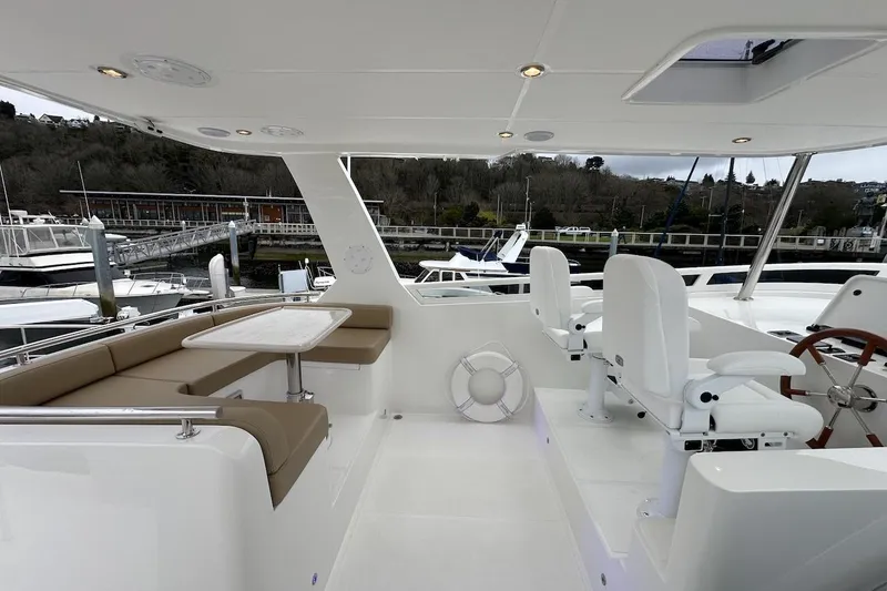 Slide: The Image of Luxurious 2024 Northwest 55 yacht deck with seating and helm, docked at marina. - 77