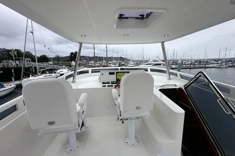 Slide: The Image of Flybridge of 2024 Northwest 55 yacht with dual white captain chairs, marina view. - 79