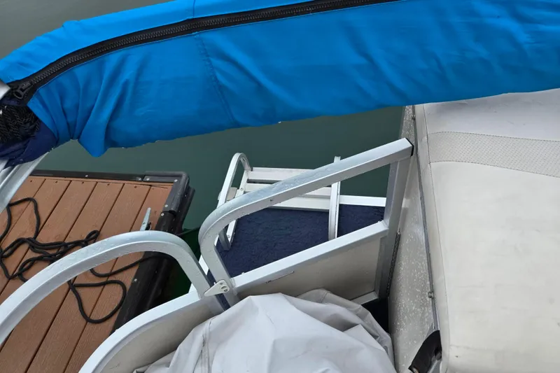 Slide: The Image of 2005 Manitou 20 Oasis boat with blue canopy and dockside view. - 15