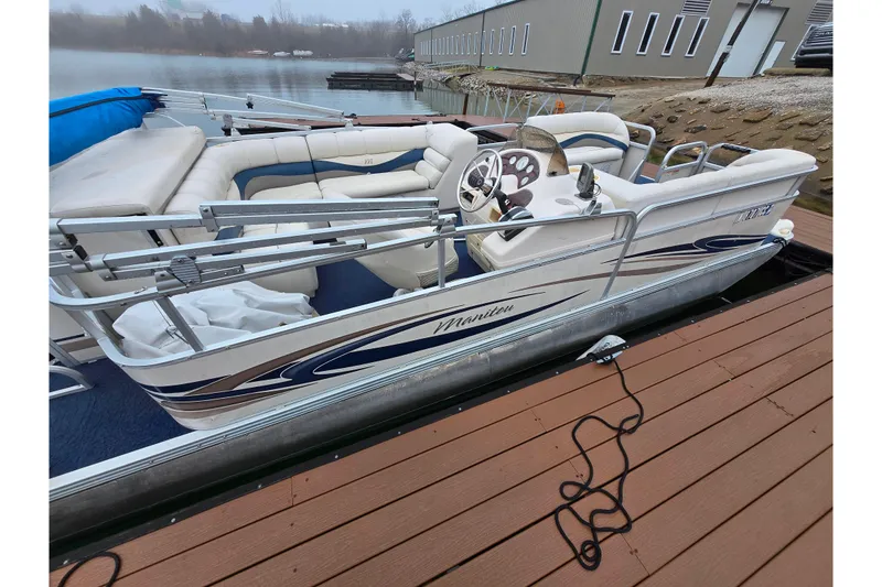 Slide: The Image of 2005 Manitou 20 Oasis pontoon boat docked by a serene lake. - 2