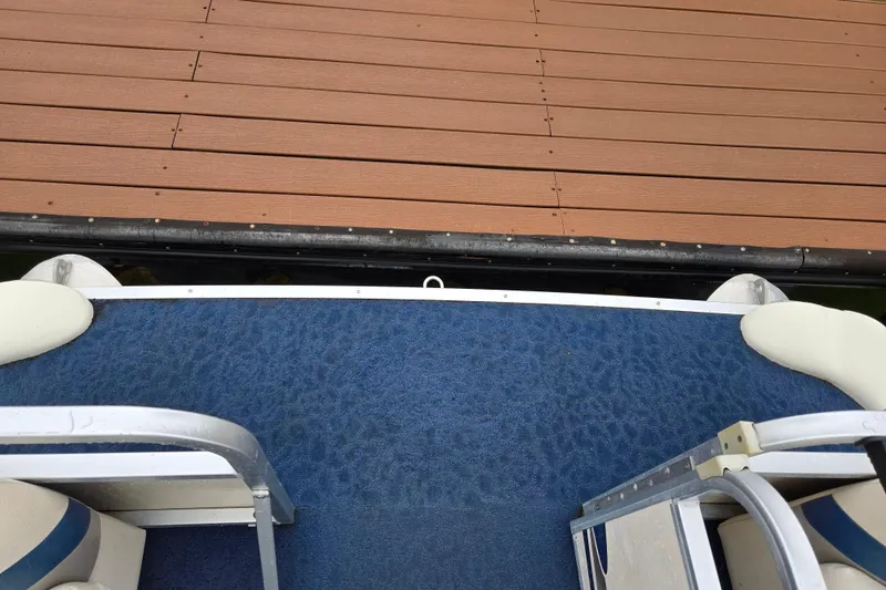 Slide: The Image of 2005 Manitou 20 Oasis pontoon boat with blue carpet near wooden dock. - 20