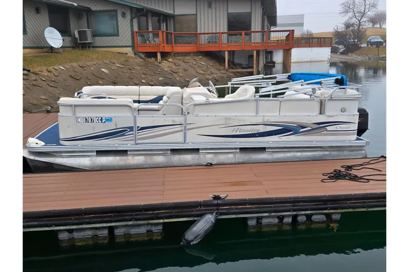 Slide: The Image of 2005 Manitou 20 Oasis pontoon boat docked by a lakeside house. - 6