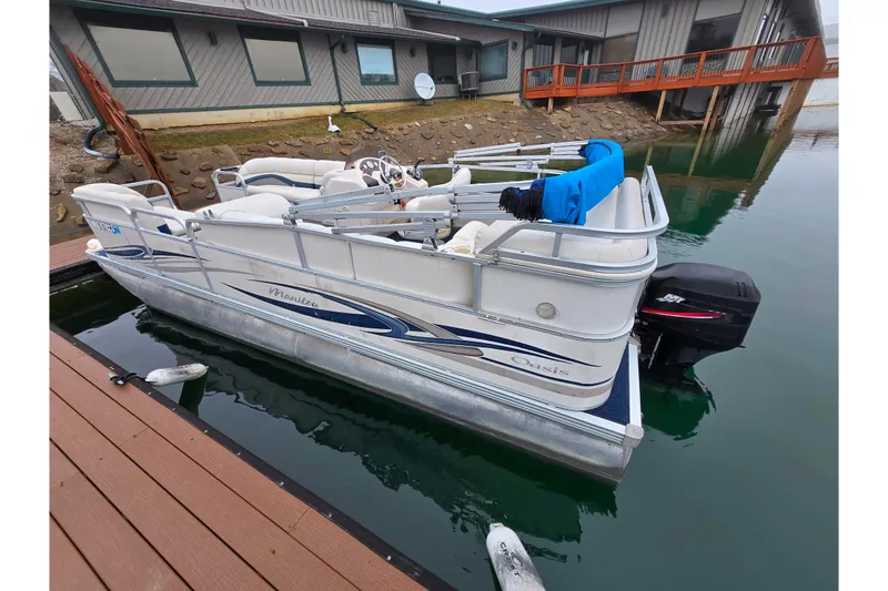 Slide: The Image of 2005 Manitou 20 Oasis pontoon boat docked by a lakeside house. - 7