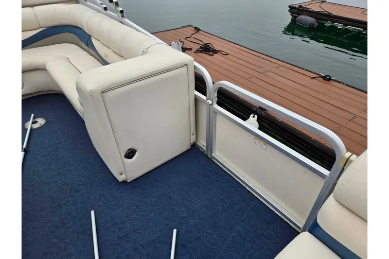Slide: The Image of 2005 Manitou 20 Oasis pontoon boat interior with blue carpet and cream seating near dock. - 9