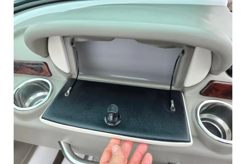 Slide: The Image of 2012 Crownline 235 SS boat dashboard with open glove compartment and cup holders. - 15
