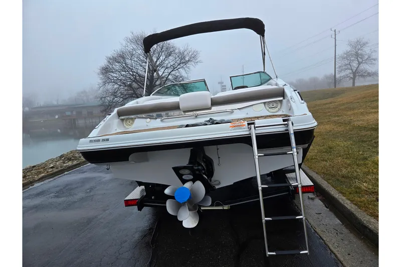 Slide: The Image of 2012 Crownline 235 SS boat with ladder, parked on a wet road near a foggy lake. - 2