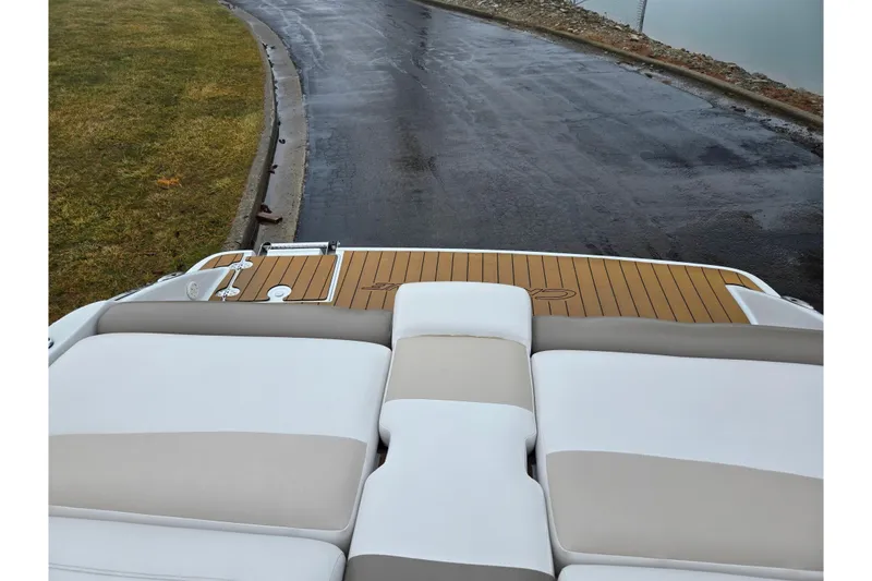 Slide: The Image of 2012 Crownline 235 SS boat with cushioned seating and wooden deck, near a wet road. - 25