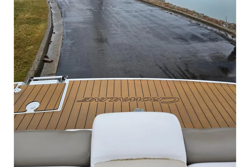 Slide: The Image of 2012 Crownline 235 SS boat with teak deck, near wet pavement and water. - 28