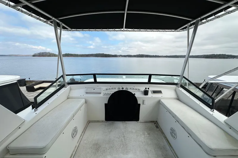 Slide: The Image of 2005 Sumerset 16x68 houseboat helm with lake view, featuring spacious seating and canopy. - 17