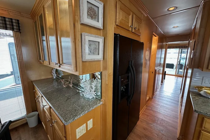 Slide: The Image of 2005 Sumerset 16x68 houseboat kitchen with wooden cabinets, granite countertops, and black refrigerator. - 5