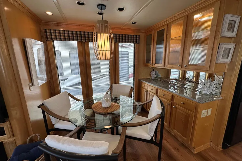Slide: The Image of Dining area in 2005 Sumerset 16x68 houseboat with glass table and wooden cabinetry. - 6