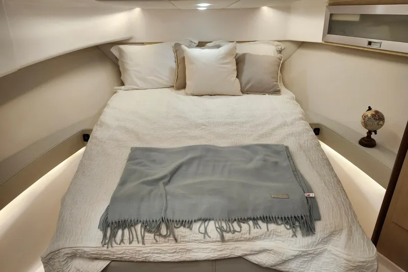 Slide: The Image of Cozy cabin interior of 2025 Regal 36 XO yacht with plush bedding and ambient lighting. - 43