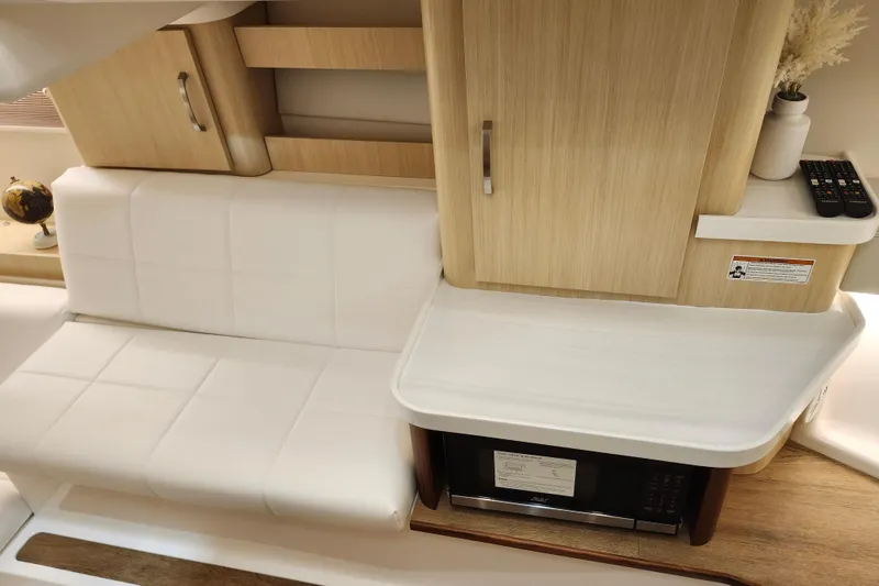 Slide: The Image of 2025 Regal 36 XO yacht interior with white seating, wooden cabinetry, and microwave. - 51